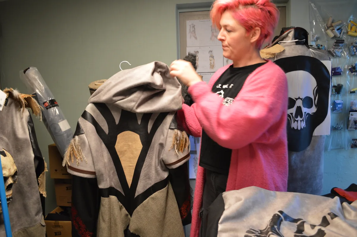 Die Modedesignerin hat eine Jacke in der Hand.